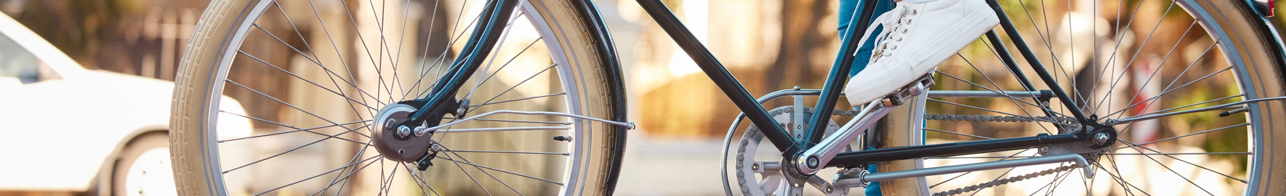 スニーカーを履いた人物が自転車のペダルに足を乗せている様子